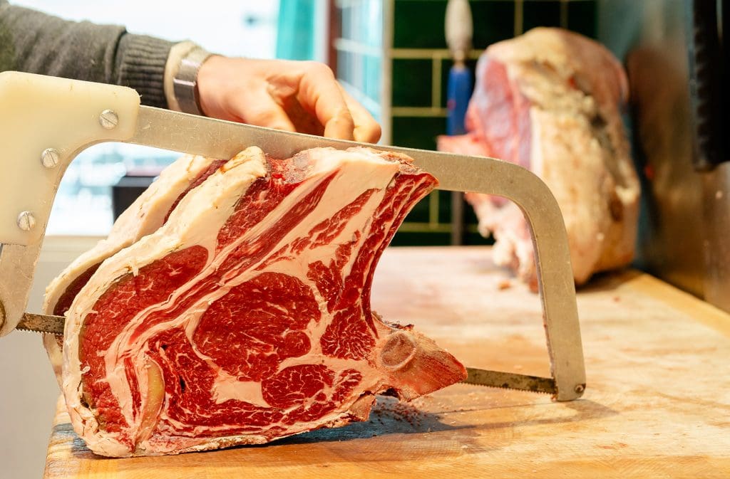 man cutting up meat on chopping board at ellis butchers